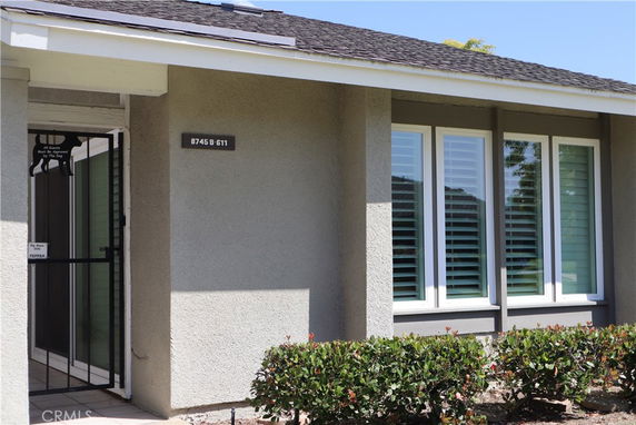 Front view of a house with large windows and a secure entry gate.