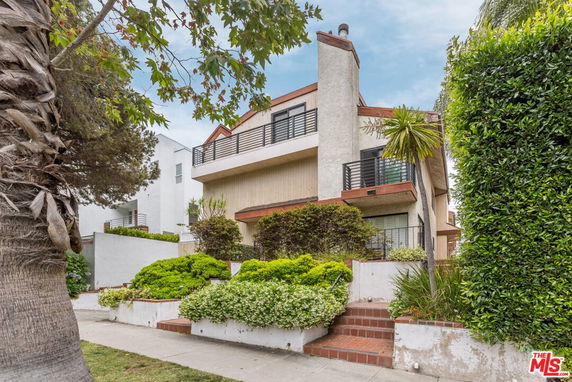 Front view of a multi-story house with balconies and landscaped entrance.