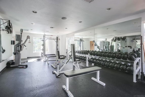 Interior view of a gym area with fitness equipment and wall mirrors.