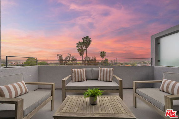Outdoor seating area with panoramic view of trees and sunset.