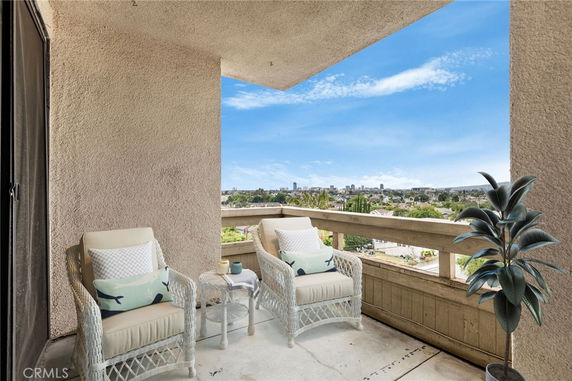 Balcony view with seating area overlooking city skyline.