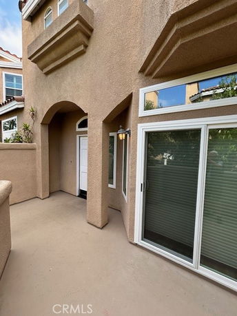 Front view of a house with an arched entryway and sliding glass doors.