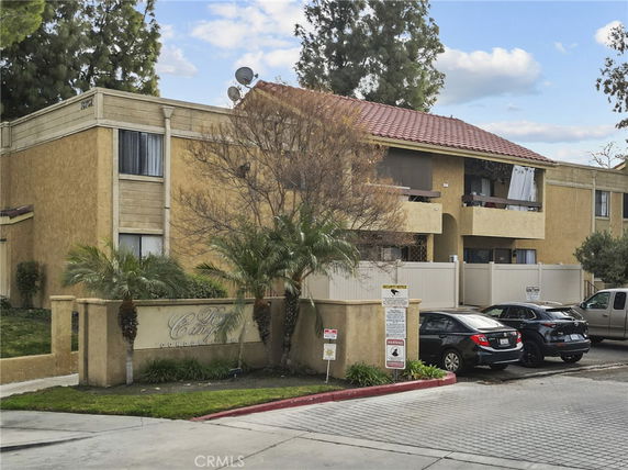 Front view of a multi-story condominium building with a tiled roof and balconies.