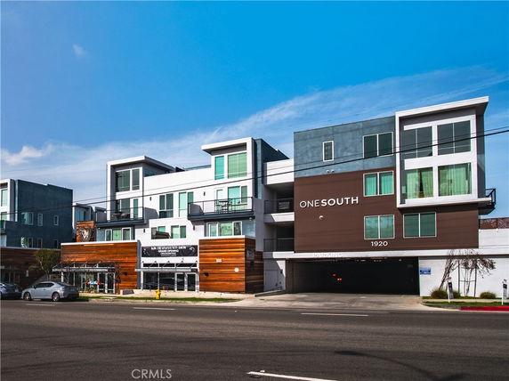 Front view of a modern, multi-story building with large windows and multiple balconies.