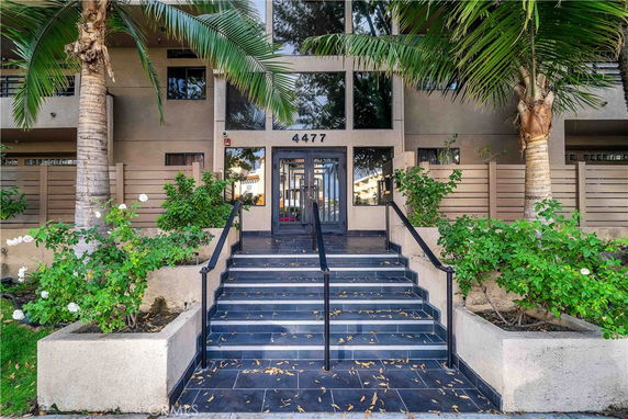 Front view of a multi-story building entrance with stairs and glass door.