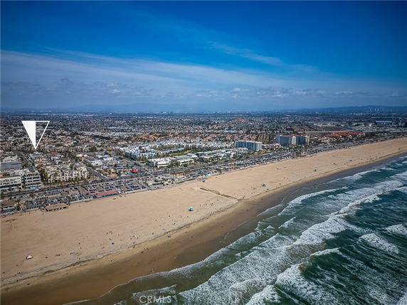 Panoramic view of a coastal city with a sandy beach and ocean waves.