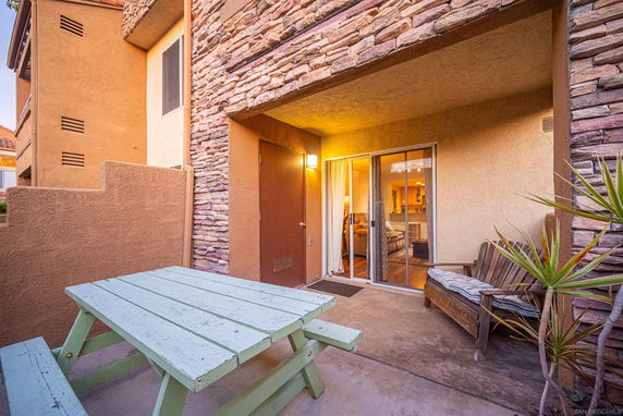Outdoor area with a stone facade and sliding glass door leading to the inside.