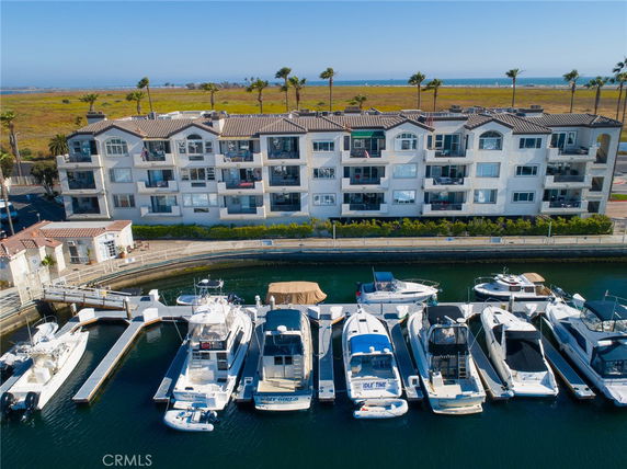 Front view of a multi-story building with balconies and marina in front.
