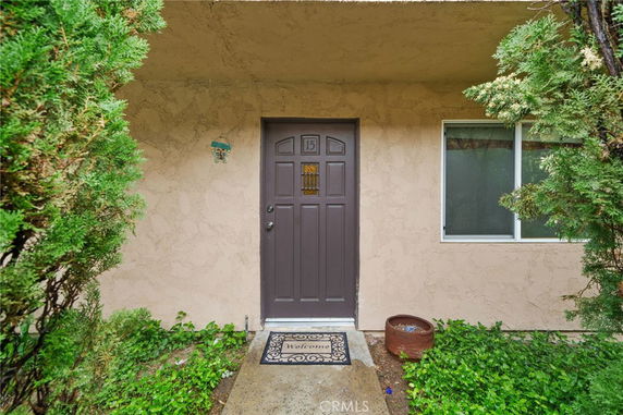 Entrance view of a house with a brown door and a window beside it.
