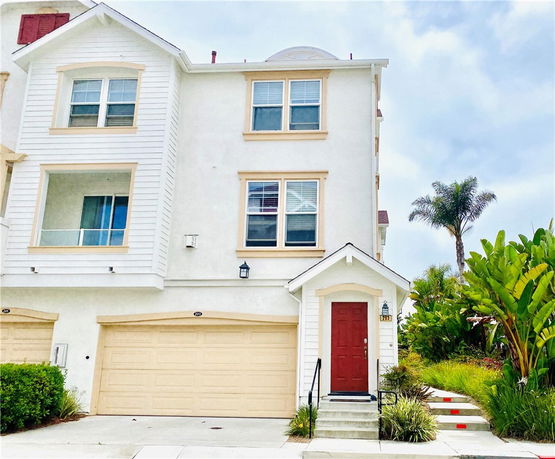 Front view of a multi-story house with a garage and red front door.