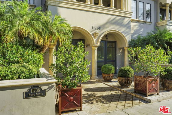 Front view of a building entrance with columns and potted plants.