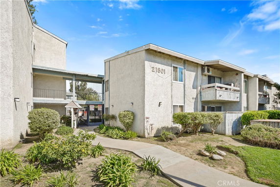Front view of a multi-story apartment building with balconies and a gated entrance.