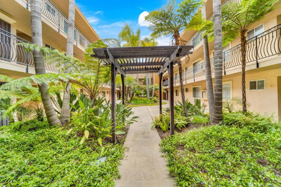 Courtyard view with walkway, plants, and apartment balconies.