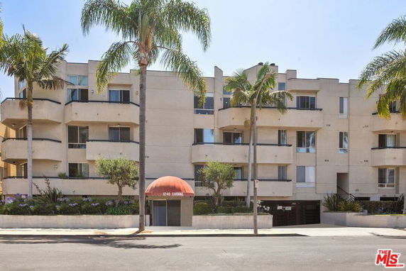 Front view of a multi-story residential building with balconies and a central entrance.