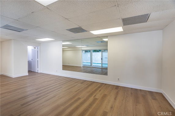 Room with wooden flooring, mirrored wall, and ceiling lights.