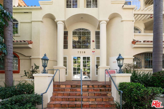 Front view of a building with arched entrance and stairway leading to the main door.