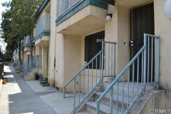 Front view of a row of multi-story townhouses with metal railings and steps.
