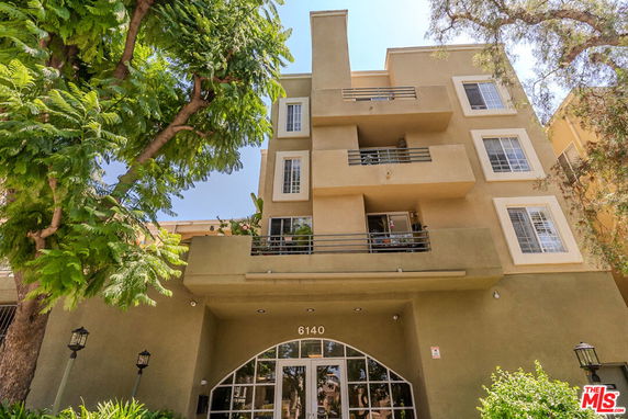 Front view of a multi-story building with balconies and large windows.