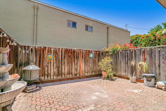Paved outdoor area with wooden fence and potted plants.