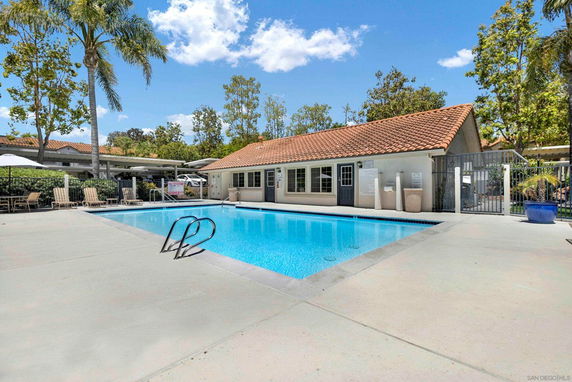 Outdoor swimming pool with adjacent building and surrounding trees.