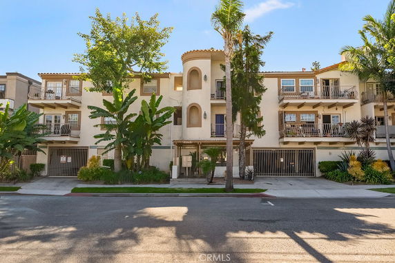 Front view of a multi-story building with balconies and garage entrances.