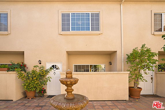 Front view of a two-story building with a courtyard and fountain.