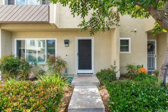 Front view of a house with a dark front door and surrounding greenery.