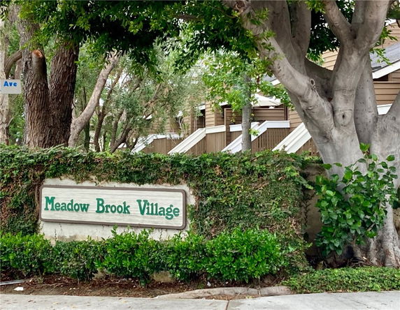 Front view of a residential area with signage for Meadow Brook Village.
