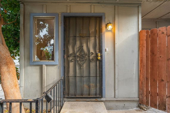 Front view of a house entrance with a metal security door and adjacent window.
