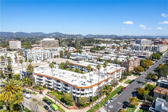 Aerial view of a residential and commercial area with multiple buildings, palm trees, and surrounding landscape.
