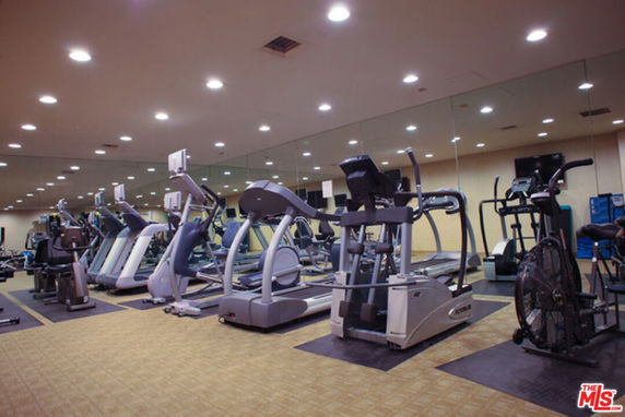 Interior view of a gym with exercise equipment and mirrors.