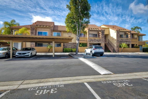 Front view of a two-story building with covered parking spaces.