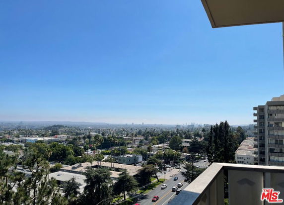 Wide-angle view from a building balcony overlooking a cityscape.