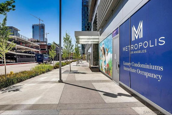 Front view of a large modern building with a luxury condominium advertisement.