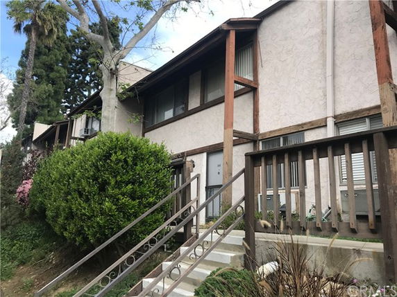 Front view of a two-story house with a wooden railing and a staircase.