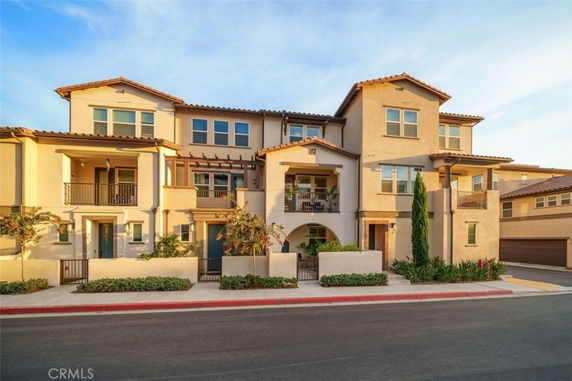 Front view of a multi-story residential building with balconies and tiled roof.