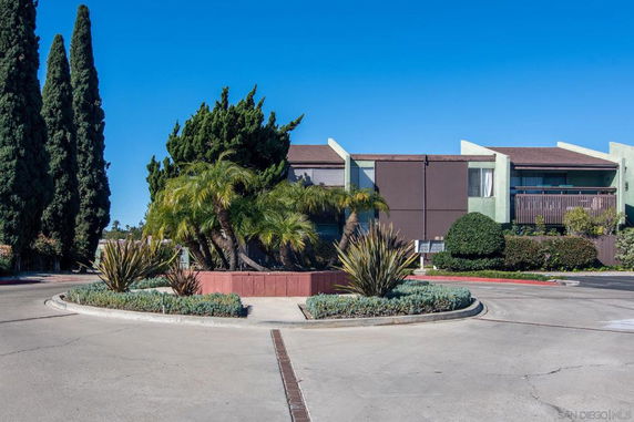 Front view of a two-story residential building with a landscaped circular driveway.
