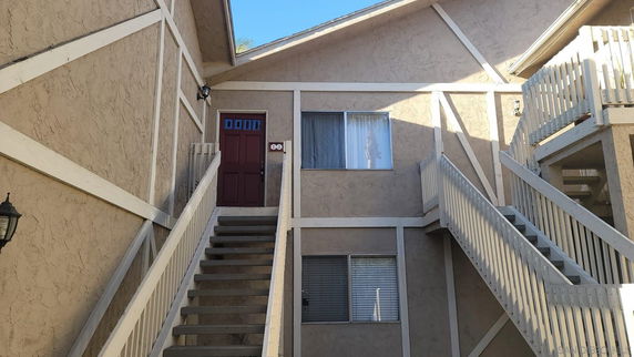 Front view of a multi-story building with external stairs and a red door.