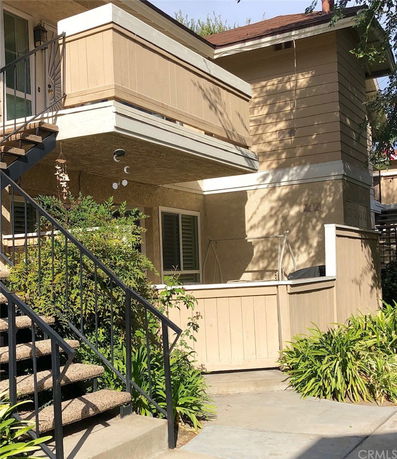 Front view of a two-story building with stairs leading to an upper balcony.