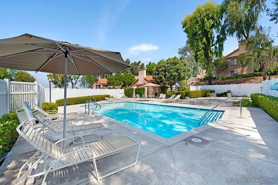 Outdoor swimming pool with lounge chairs and a large umbrella.