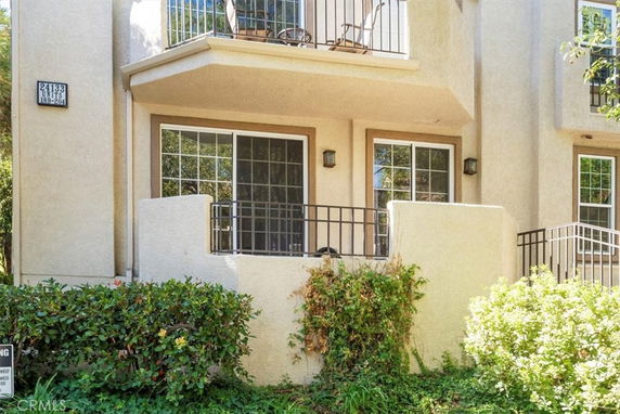 Front view of a multi-story building with balconies and sliding glass doors.