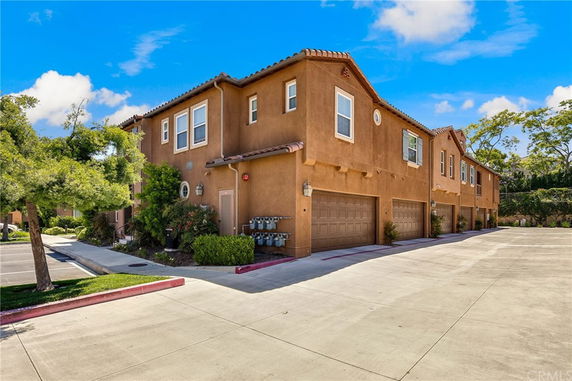 Front view of a two-story residential building with a stucco exterior and garages.