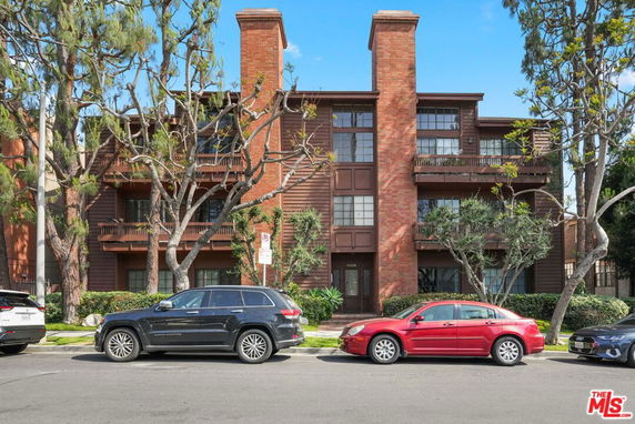 Front view of a multi-story residential building with a brick and wood exterior.