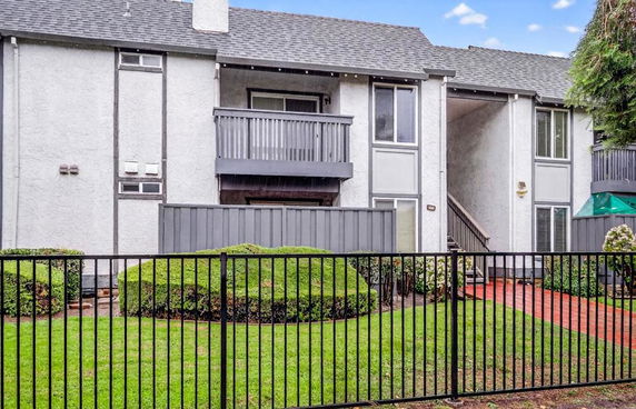 Front view of a two-story residential building with balconies and a gated entrance.