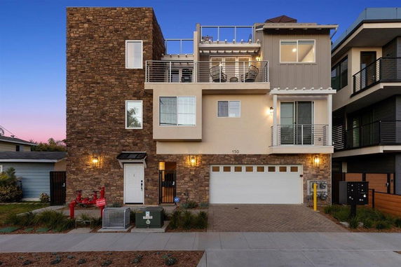 Front view of a modern multi-story house with stone and stucco exterior and a double garage.