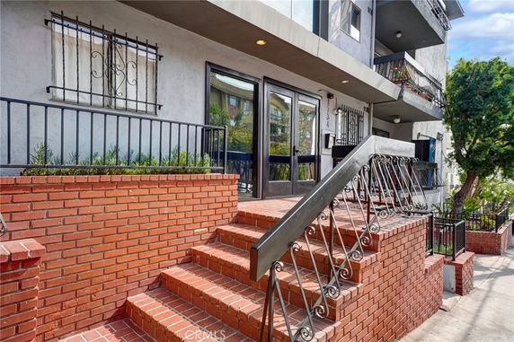Front view of a multi-story building with red brick steps and iron railings.