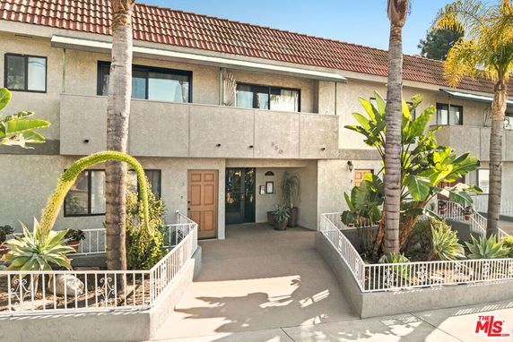 Front view of a two-story building with balconies and tiled roof.
