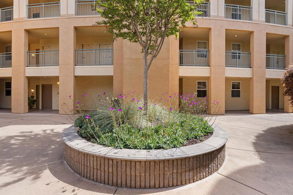 Front view of a multi-story building with balconies and a central courtyard with a garden.