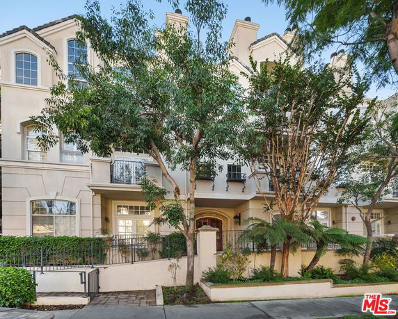 Front view of a multi-story townhouse with a landscaped front entrance.