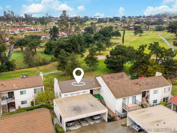 View of residential buildings with a golf course and trees in the background.